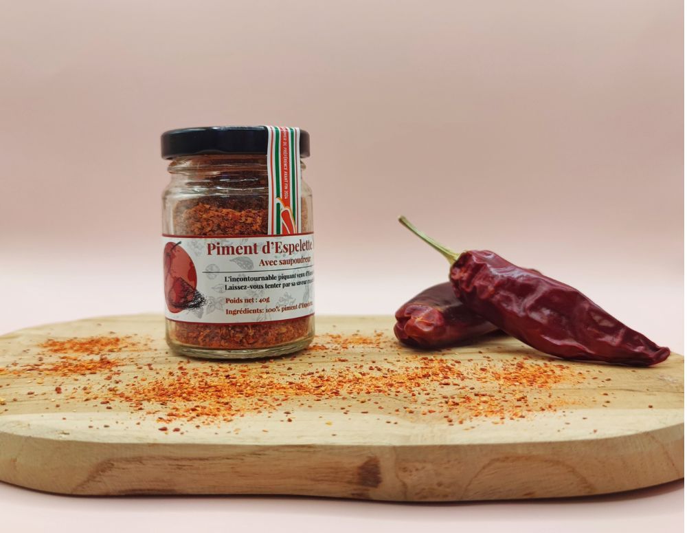 Piment d'Espelette AOP Origine France 100g, présentation dans un pot sur planche en bois avec piments d'Espelette entiers